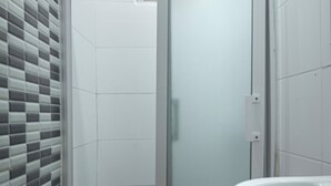 Une salle de bain avec une douche à parois de verre, un abattant de toilettes rouge et un lavabo blanc.