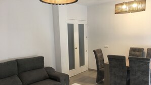 Una sala moderna con un sofá gris, una mesa de centro blanca y sillones tapizados en gris.