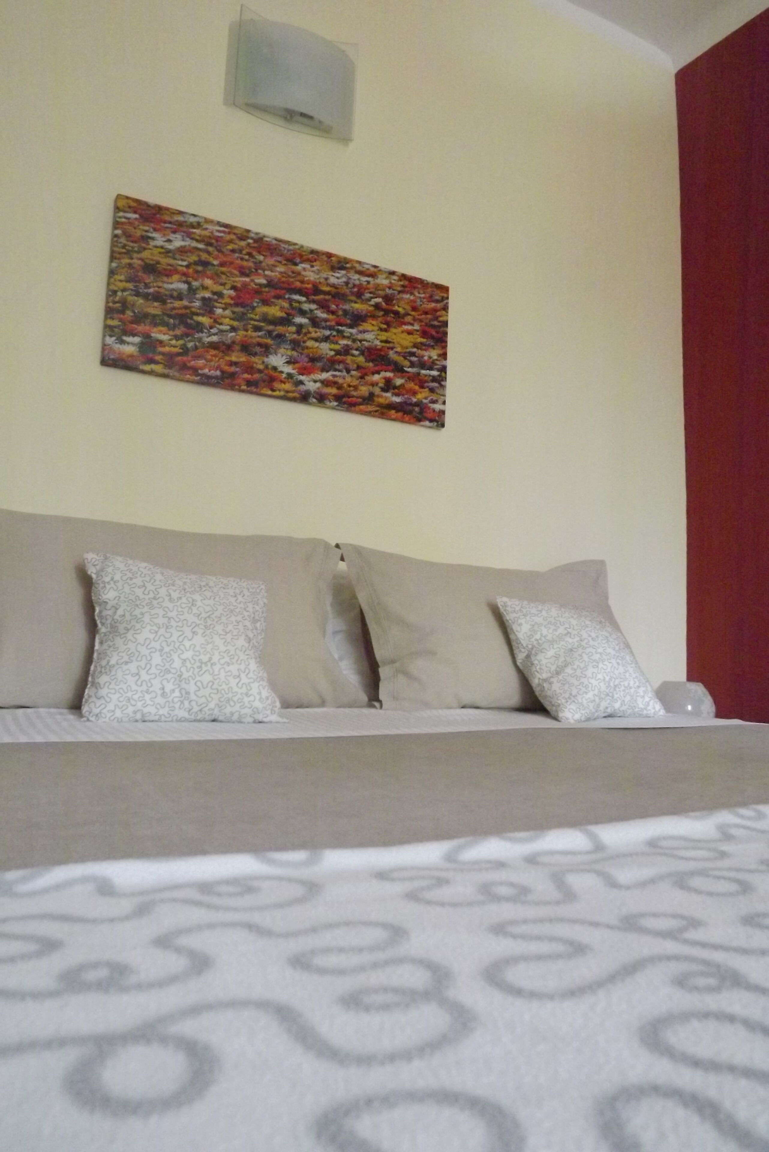 A bedroom with a bed, a sofa, and a wall-mounted artwork.
