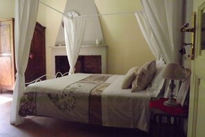 A bedroom with a four-poster bed, a bedside table with a lamp, and a fireplace. - B&B Lunigiana & Cinque Terre: pool, typical dinners, wellness family&friends (Tresana)