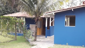 Un edificio azul con techo de tejas, un porche cubierto y una ventana pequeña.