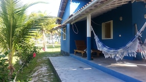 Una casa azul con un porche, una hamaca y un banco de madera.