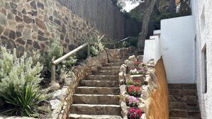 A stone staircase with steps leading up to a white building, surrounded by plants and flowers. - BEAUTIFUL HOUSE SEA VIEWS (Tossa de Mar)