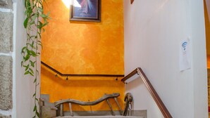 A staircase with a wooden handrail, a picture on the wall, and a plant on the left. -  Rural accommodation Solar dos Marcos (Bemposta Mogadouro)