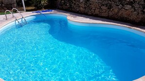 A clear blue swimming pool with a stone wall and metal ladder. -  Rural accommodation Solar dos Marcos (Bemposta Mogadouro)