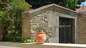 A stone building with a metal gate, surrounded by greenery. -  Rural accommodation Solar dos Marcos (Bemposta Mogadouro)