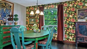 A dining area with a round table, chairs, and a window with curtains.
