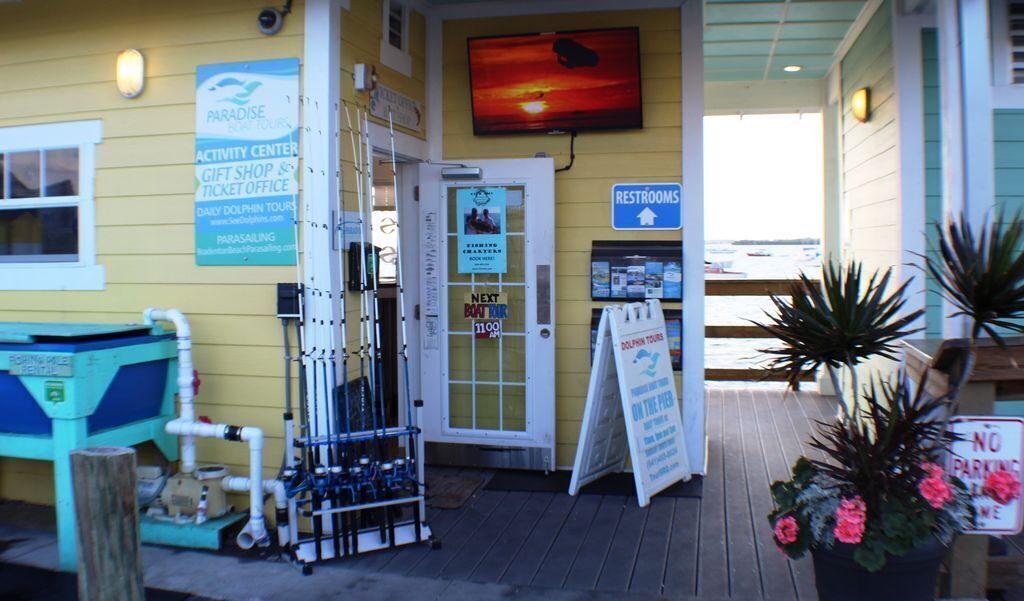 A building with a sign for a dolphin tour, a gift shop, and a ticket office.