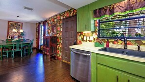 A kitchen with green cabinets, a dishwasher, and a window with a floral pattern. - LAST MINUTE DEALS! FREE WIFI I  Banyan – Peaceful 1BR Getaway Near Beaches, Bays & Dining (Bradenton)