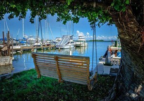 A wooden bench by a dock with boats in the background.