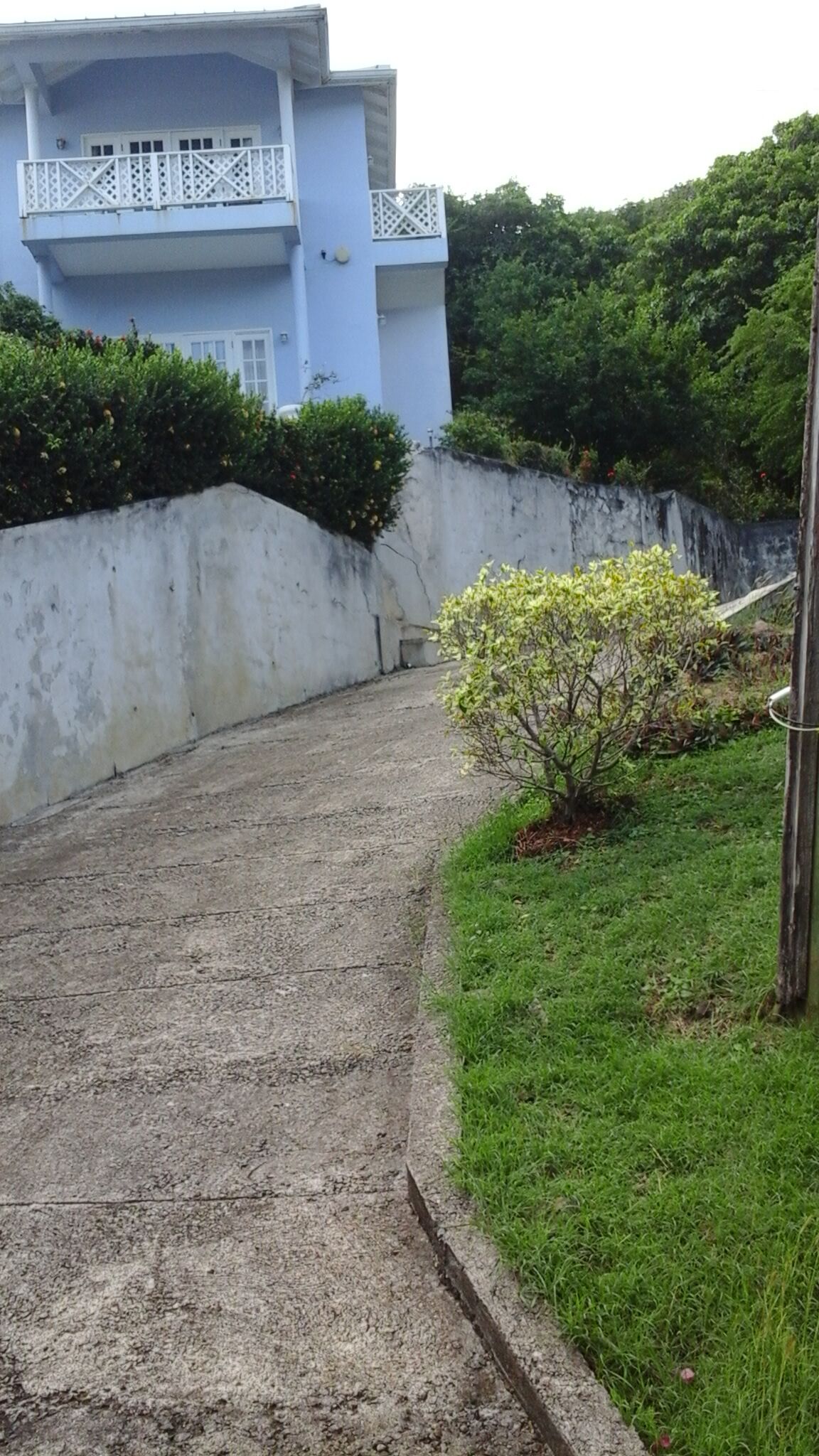 A concrete pathway leading to a blue building with a white balcony.