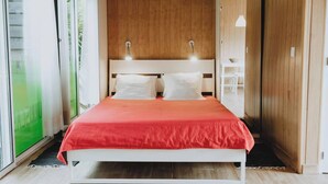 A modern bedroom with a white bed, red bedding, and wooden paneling on the walls. - Bungalow (Montemor-o-Novo)