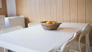 A white table with a woven basket containing fruits, set against a wooden wall. - Bungalow (Montemor-o-Novo)