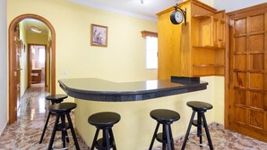 Una cucina con angolo bar, mobili in legno e un orologio.