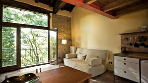 A cozy living area with a sofa, a wooden table, and a view of trees through large windows.