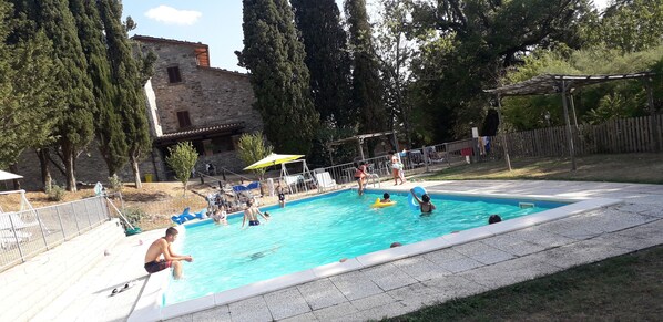 Una piscina rodeada por un edificio de piedra y árboles.