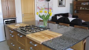 Una cocina con una isla central, armarios de madera, una estufa a gas y un jarrón con flores amarillas.