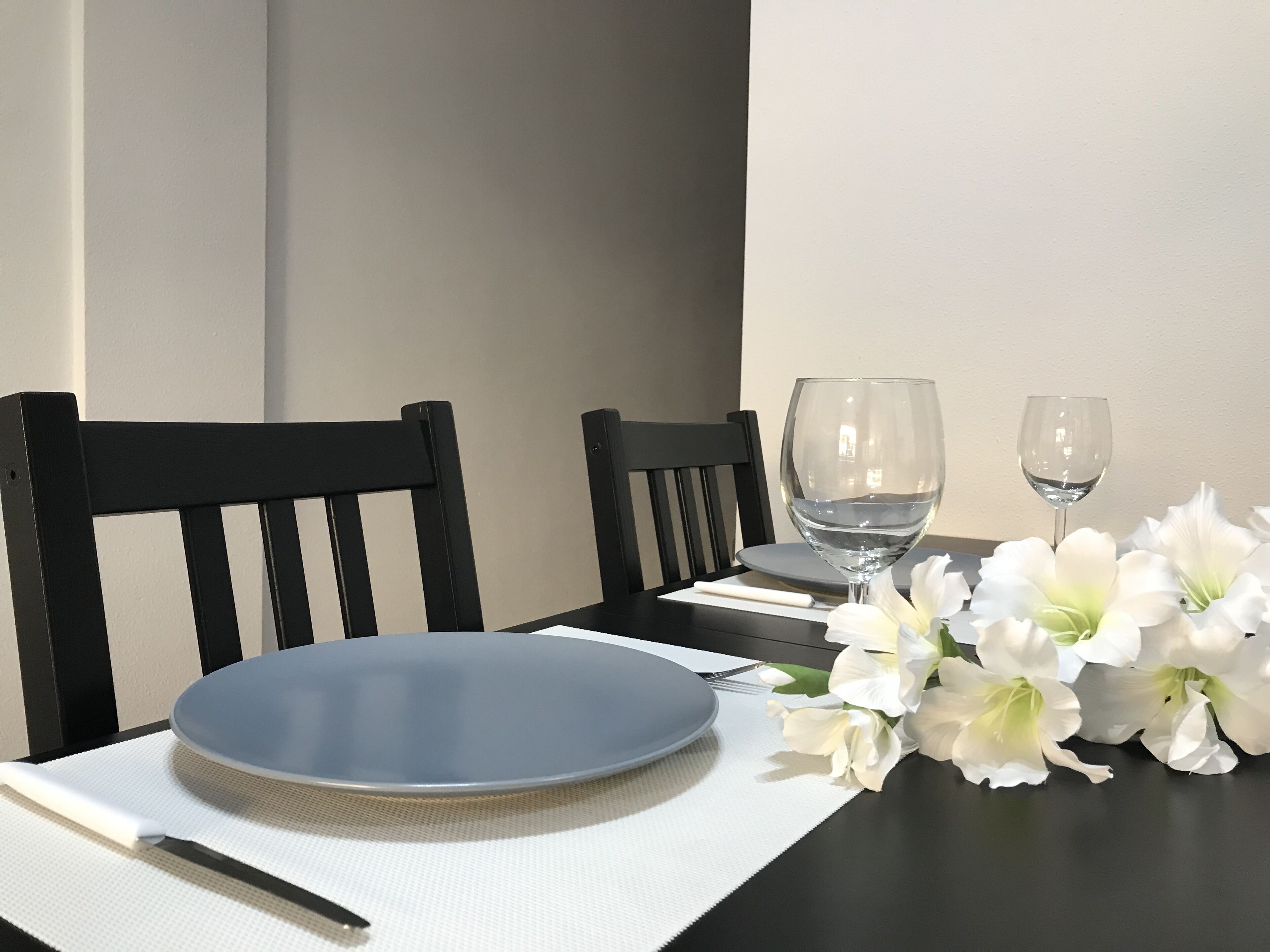 A table set with a blue plate, two wine glasses, a fork, and a napkin.
