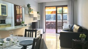 Een moderne woonkamer met een eetgedeelte, een keuken en een schuifdeur naar een terras.