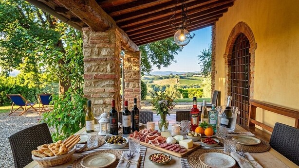 An outdoor dining area with a stone wall, wooden beams, and a view of the countryside. - Villa Carmignani, your home in Tuscany: exlusive use of villa, grounds and pool. (San Casciano in Val di Pesa)
