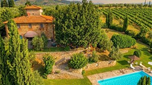 A villa with a stone exterior, a swimming pool, and a vineyard in the background. - Villa Carmignani, your home in Tuscany: exlusive use of villa, grounds and pool. (San Casciano in Val di Pesa)