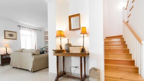 A living room with a sofa, a table with lamps, a staircase, and a mirror on the wall. - Gomes Freire Terrace (Cascais)