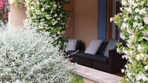 A cozy outdoor seating area with a cushioned bench and a stone ledge. - Villa du Moulin with private swimming pool (Saumane de Vaucluse)