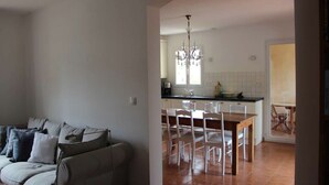 A living room with a sofa and chairs, a dining area with a table and chairs, and a kitchen with a chandelier and tiled backsplash. - Villa du Moulin with private swimming pool (Saumane de Vaucluse)