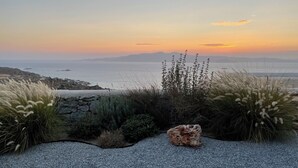 Un sendero de grava que conduce a un afloramiento rocoso con vistas al mar y montañas distantes.