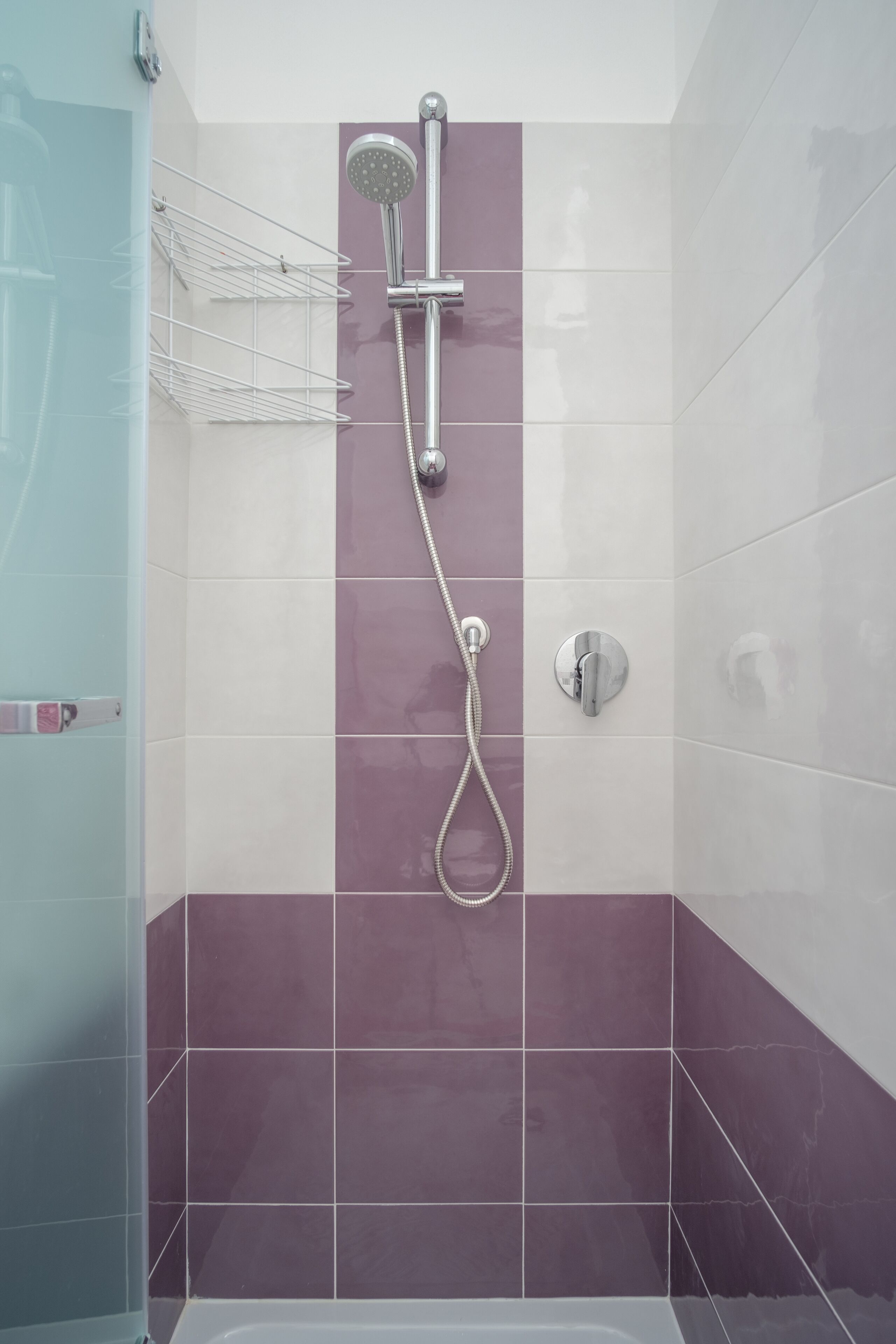 A shower with a handheld showerhead and a wall-mounted faucet.