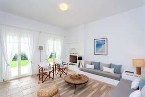 A spacious living room with a sofa set, a dining area with chairs, a fireplace, and a view of the outdoors.