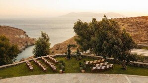 A coastal outdoor seating area with stone flooring and potted plants. - On The Rocks - The Two Rocks - Serviced Villa (Ios)
