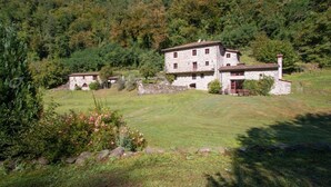 A stone building with a red door, surrounded by a grassy area and trees. - Fantastic family villa with pool.... (Barga)