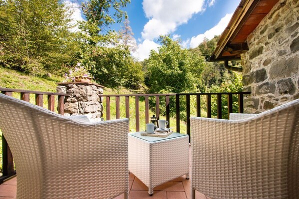 A patio with wicker furniture and a stone pillar, overlooking a lush green landscape. - Fantastic family villa with pool.... (Barga)