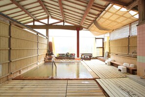 Un onsen japonés tradicional con suelos de madera y barandillas de bambú.