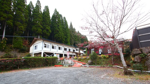 A building with a porch and a driveway leading to a gated entrance. - Senju no sato Ramune Onsen (Kirishima)