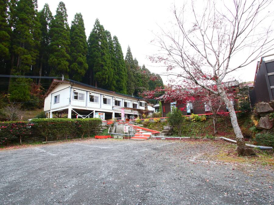 A building with a porch and a driveway leading to a gated entrance.