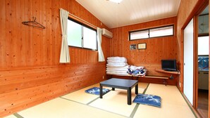 A traditional Japanese room with tatami flooring, a small table, a TV, and a window with curtains. - Senju no sato Ramune Onsen (Kirishima)