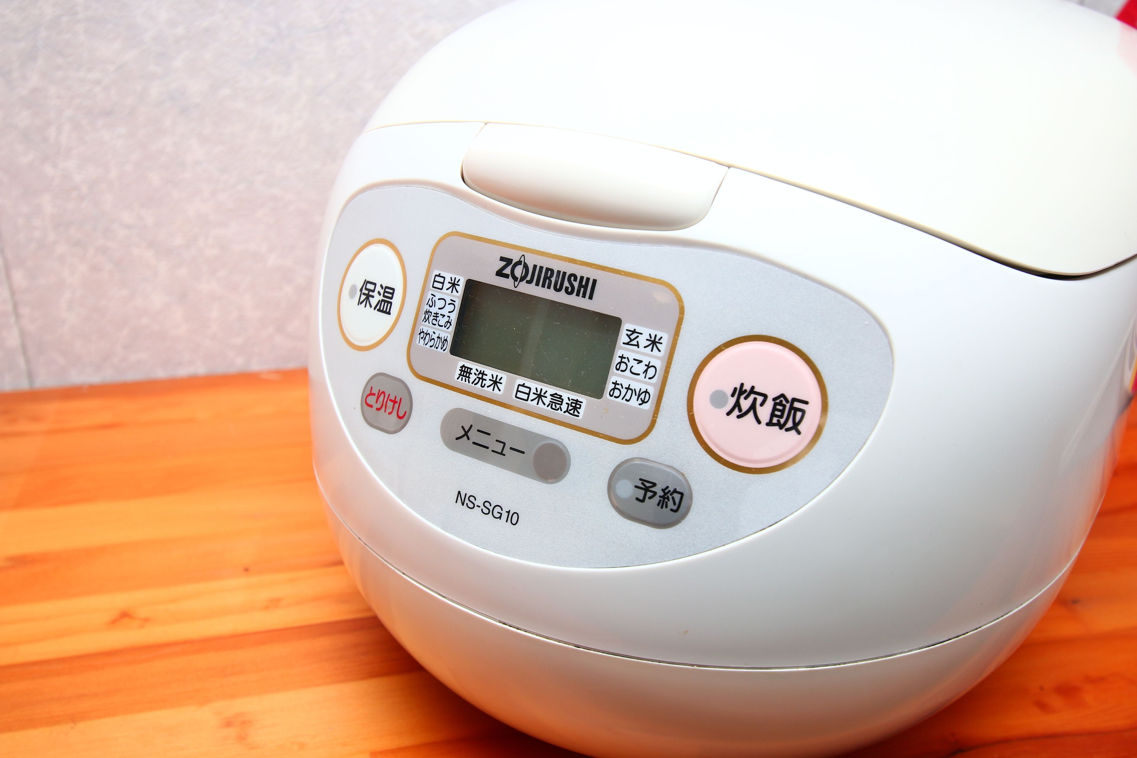 A rice cooker with a digital display and multiple buttons, including settings for white rice, brown rice, and a timer.