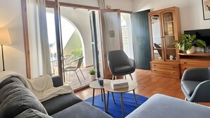 Una sala de estar moderna con un sofá, dos sillones, una mesita, un mueble y un televisor.