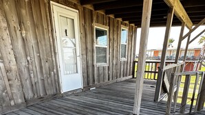 A wooden deck with a covered area, featuring a door and windows. - Surfside Beach, Texas. Fantastic views of the beach and bay. Steps to the beach (Freeport)