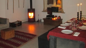 A cozy room with a fireplace, a dining table set for two, and a sofa. - Charming spacious barn in beautiful tranquil scenery, pool on property (Albalá del Caudillo)