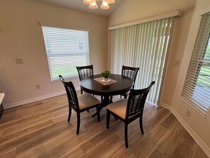 A dining area with a round table, four chairs, and a potted plant.