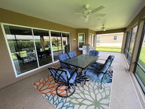 A covered patio with a table and chairs, a ceiling fan, and a view of the backyard.