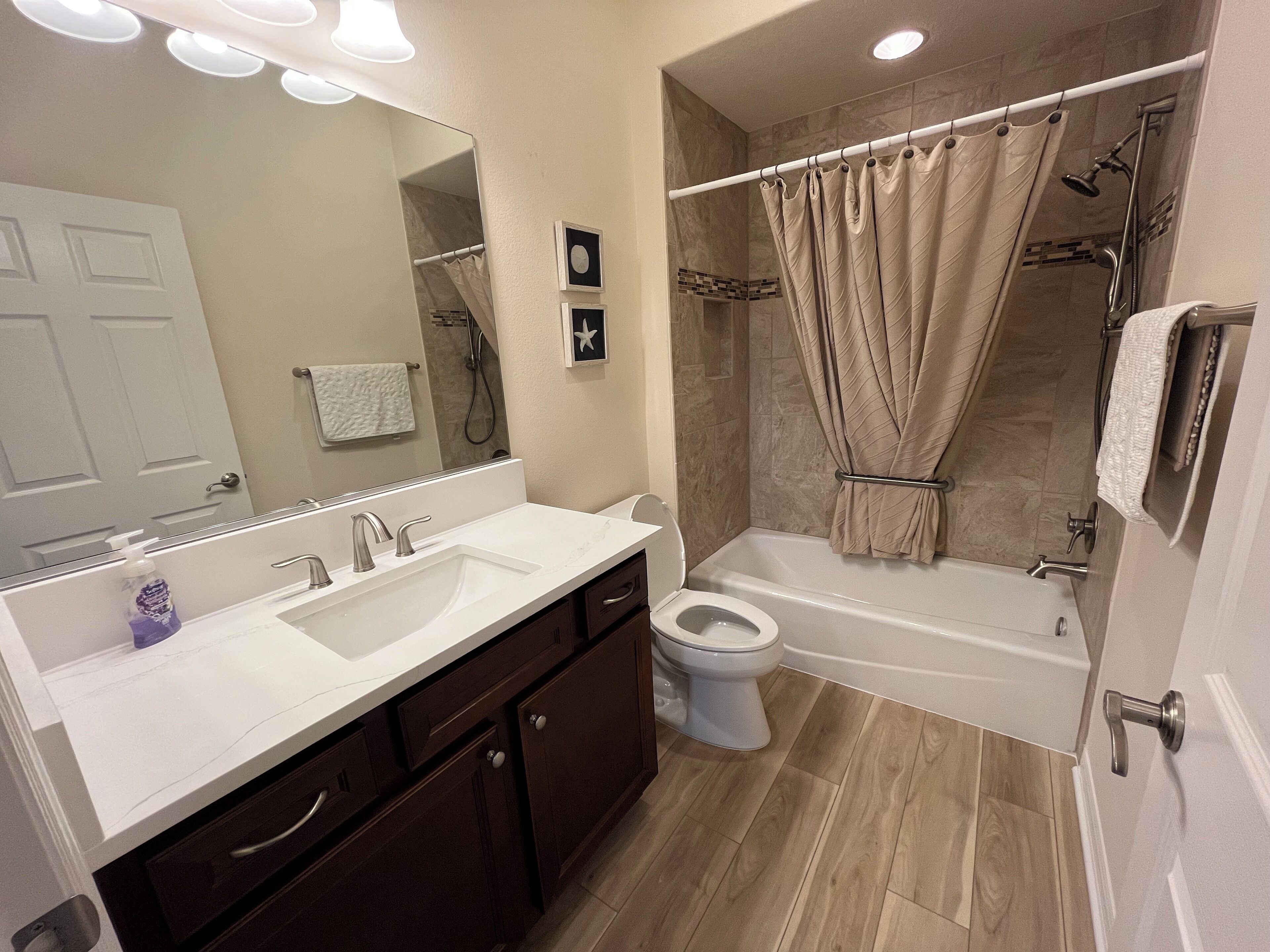 A modern bathroom with a double sink vanity, a toilet, a bathtub, and a shower area.