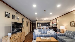 Una sala de estar con televisor, sofá y mueble de madera.