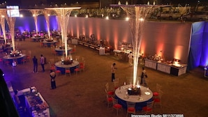 An outdoor event space with round tables, chairs, and a stage area. - The Utsav Grand Banquets & Resort (Sonepat)