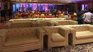 A banquet hall with rows of tables and chairs, a stage, and a seating area with sofas. - The Utsav Grand Banquets & Resort (Sonepat)
