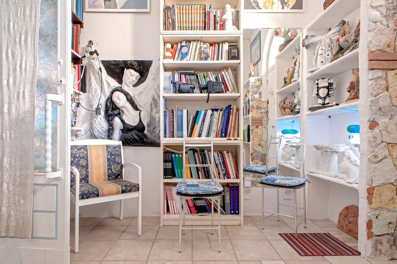 Um cantinho aconchegante para leitura, com estante, poltrona e mesa pequena.