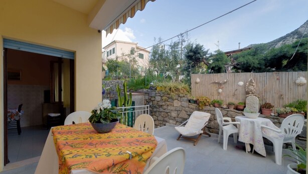 Eine Außenpatio mit Tisch und Stühlen, umgeben von Pflanzgefäßen und einer Steinmauer.